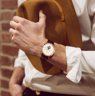 Uma mão usando um relógio Bulova e segurando um chapéu.